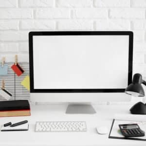 Scrivania da ufficio vista frontale con schermo del computer e lampada, ambiente di lavoro moderno e ordinato